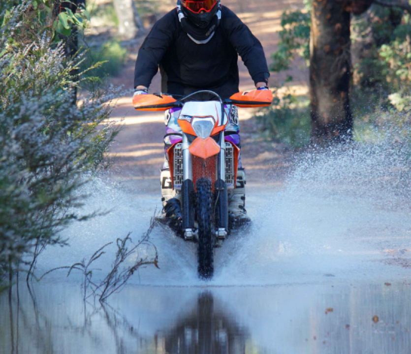 Motorcycle rider crossing a creek.
